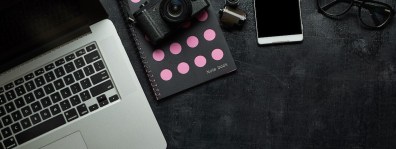 graphicstock-wooden-black-office-desk-table-with-laptop-camera-and-other-supplies-blank-notebook-page-for-input-the-text-in-the-middle-top-view_SOSZOsDeix